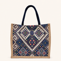 A bohemian-inspired canvas tote bag featuring navy handles, beige side trim, and a colorful geometric woven pattern.