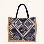 A bohemian-inspired canvas tote bag featuring navy handles, beige side trim, and a colorful geometric woven pattern.