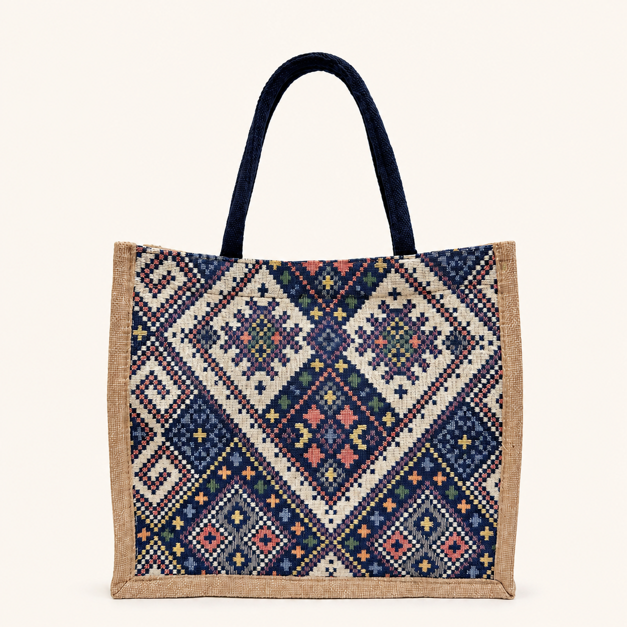 A bohemian-inspired canvas tote bag featuring navy handles, beige side trim, and a colorful geometric woven pattern.