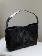 Sleek black genuine leather wide-woven work tote bag, highlighting its modern city sophistication and premium craftsmanship.