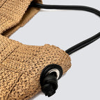 Macro detail of the black shoulder strap with a knotted end on the straw bag