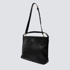 Side angle of the black woven vegan leather shoulder bag with crossbody strap