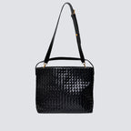 Black woven tote bag displayed with its long adjustable crossbody strap attached