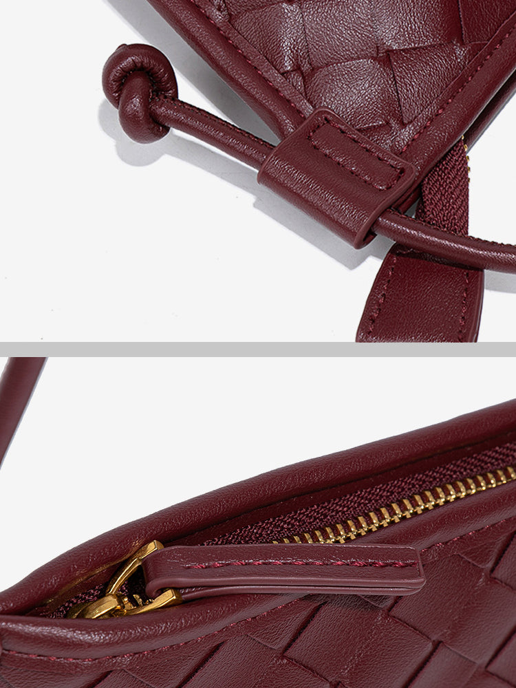 Close-up of the smooth golden zipper closure and the signature knotted strap detail on the burgundy woven vegan leather bag.