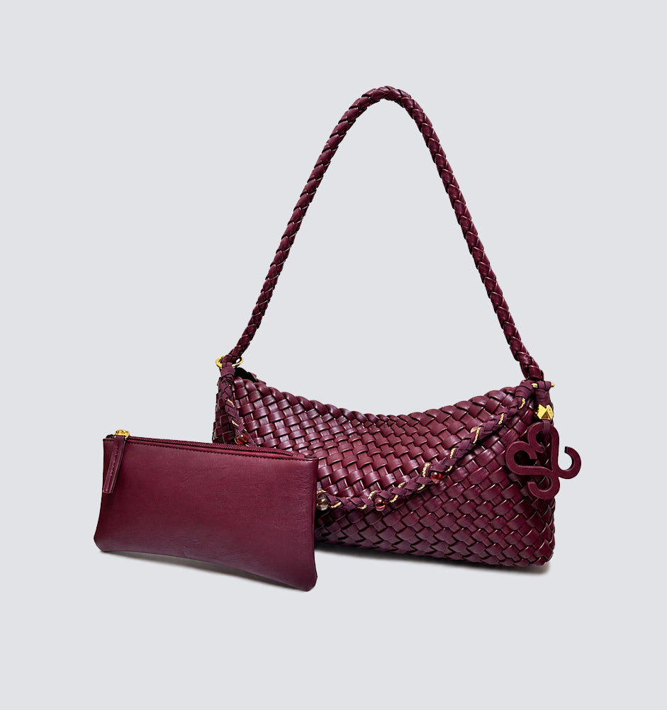 Burgundy woven baguette bag displayed next to its matching vegan leather zip pouch