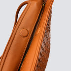 Close-up detail of the cognac woven vegan leather texture and side accent