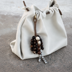 Earthy seed bag accessory styled on a soft white leather slouchy bag.