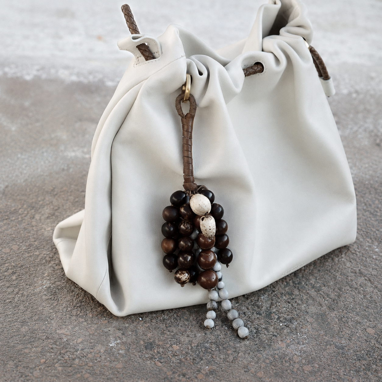 Earthy seed bag accessory styled on a soft white leather slouchy bag.