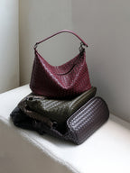 Stack of genuine leather woven bags in burgundy, olive, and brown