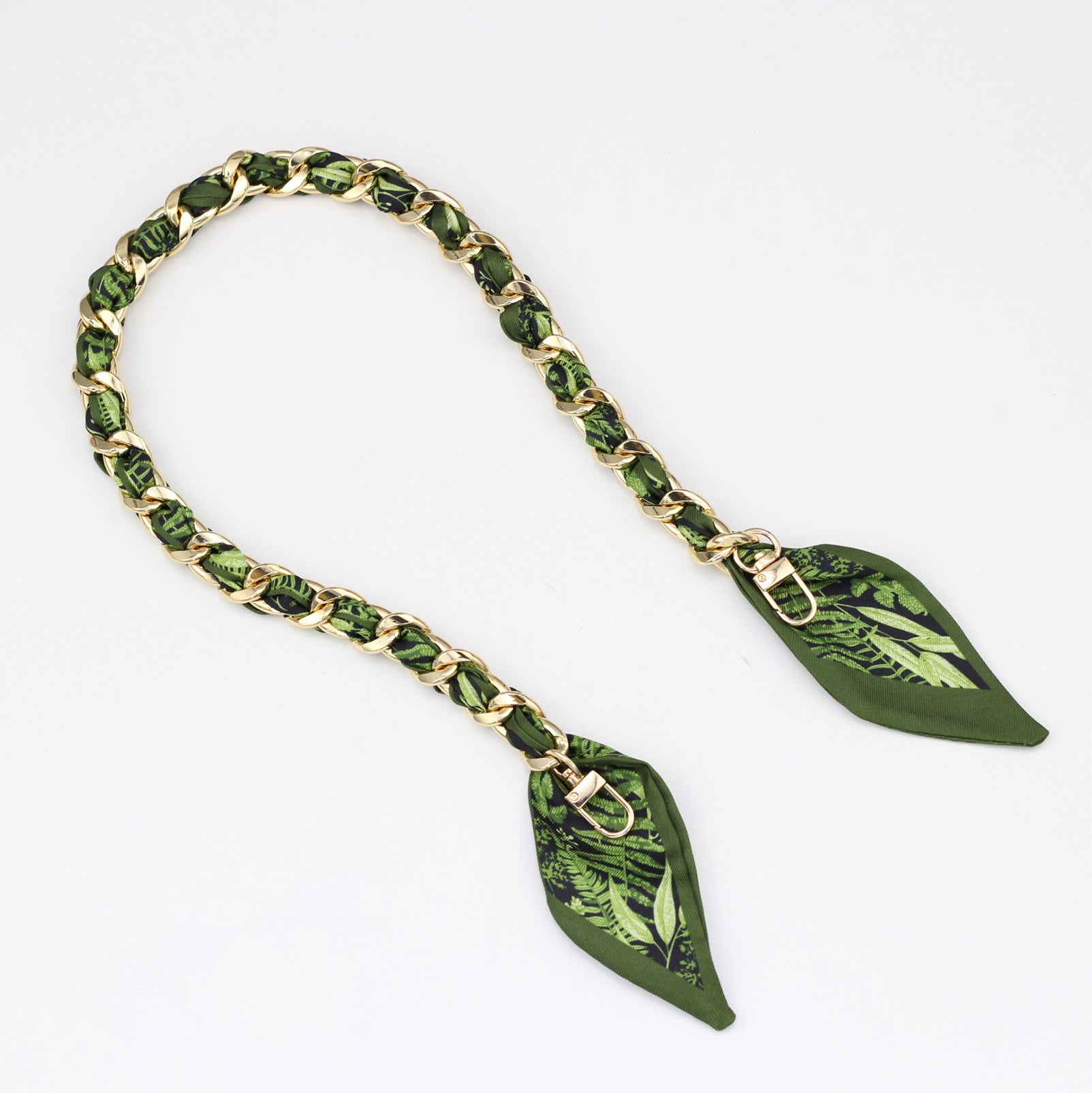Green botanical leaf print silk ribbon woven into a gold metal bag strap