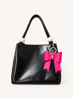 Hot pink PU bow bag charm on black handbag