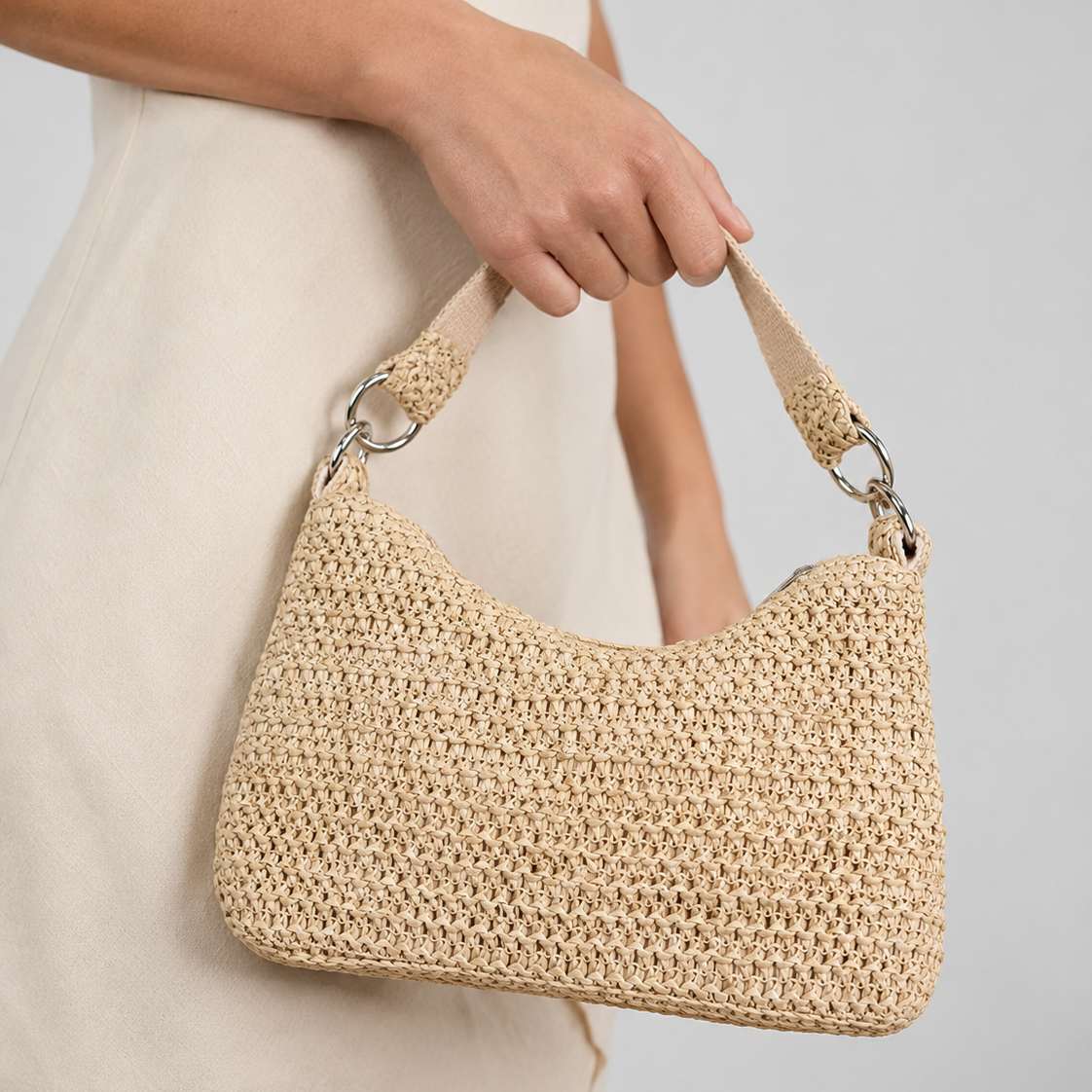 Model in a linen dress holding the lightweight woven straw shoulder bag