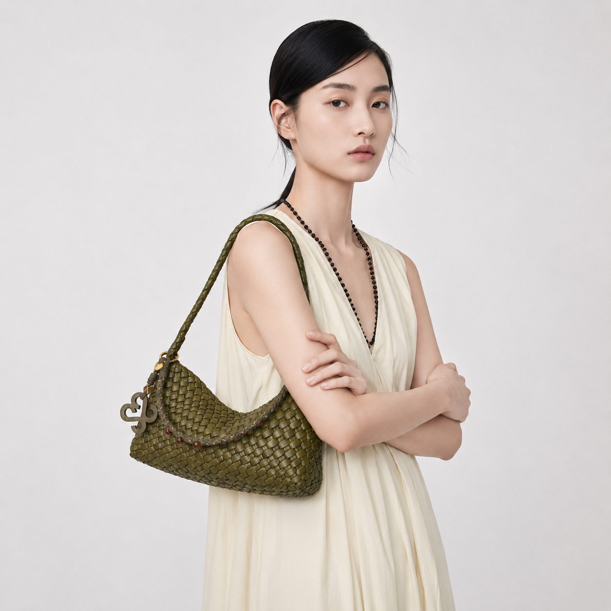 Elegant model in a beige dress carrying the THReAD olive green woven underarm bag