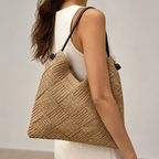 Model in a white dress wearing the natural woven straw beach tote bag on her shoulder
