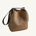Front view of a natural raffia woven hobo bag with a black genuine leather strap