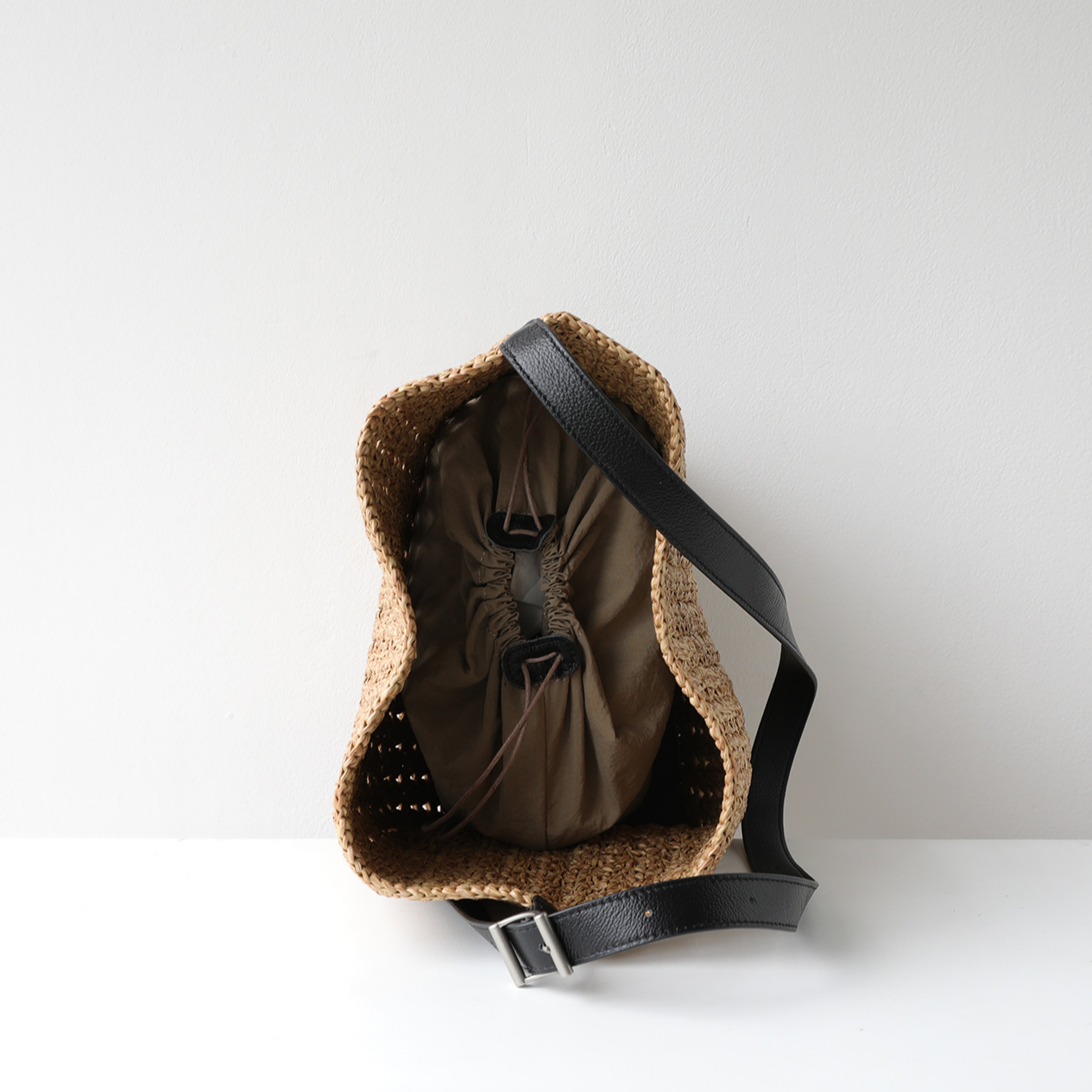 Top-down interior view of the natural raffia hobo bag showing the secure drawstring fabric lining