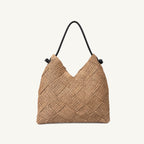 Natural woven paper straw beach tote with brown leather handles, front view