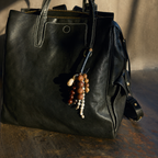 Organic texture bag charm elevating a black leather travel bag.