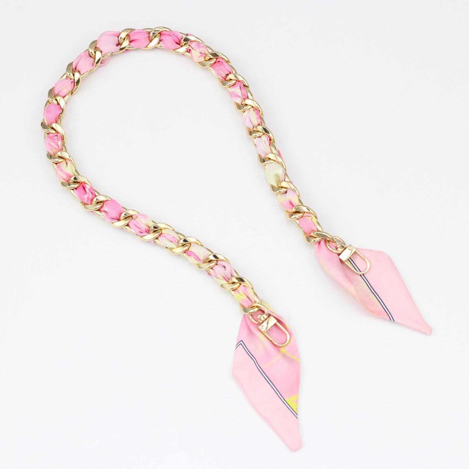 Light pink silk ribbon woven through a gold metal bag chain