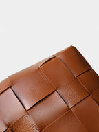 Macro close-up showcasing the luxurious genuine leather texture and the elegant wide-woven pattern on the brown tote bag.