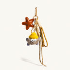 Brown vegan leather star bag charm with grey plush pom keychain and beige cord tassels