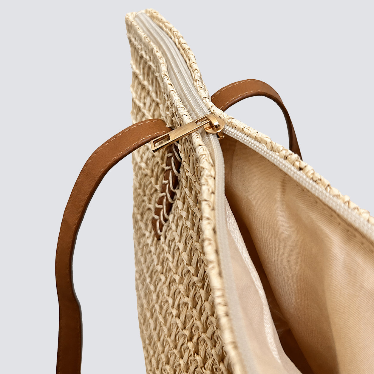 Top-down view highlighting the secure smooth zipper closure of the woven straw tote