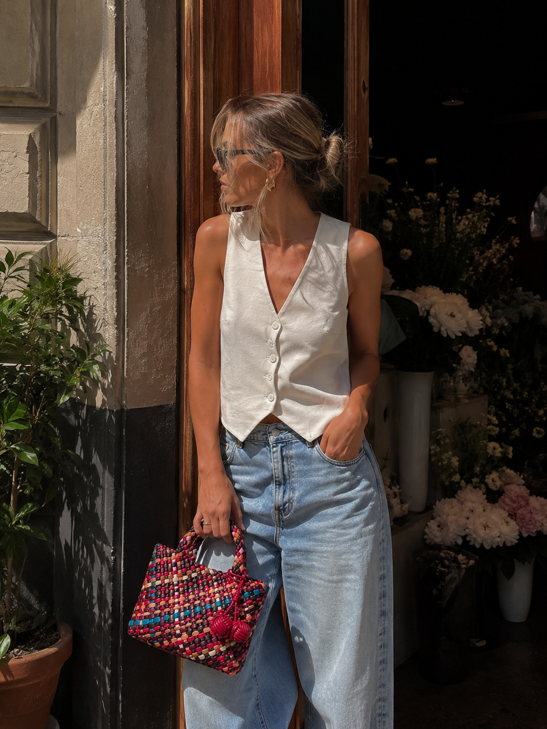 Woman holding a colorful woven tote bag in a relaxed lifestyle setting