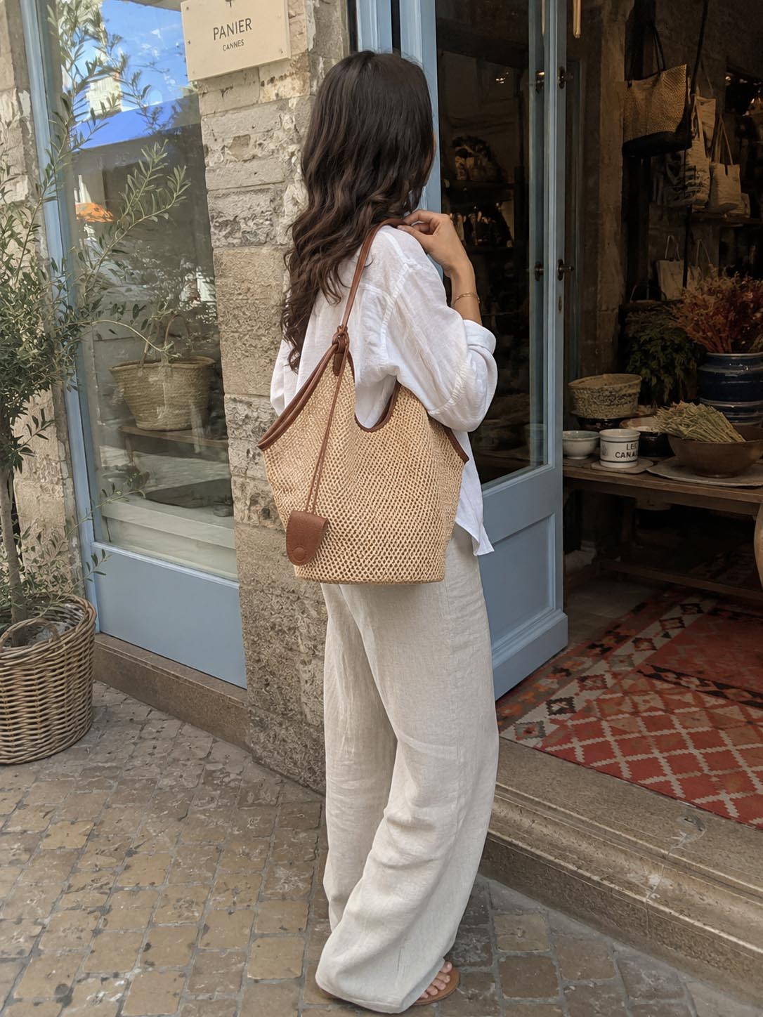 Woman carrying The Amalfi woven straw shoulder bag on a Cannes street