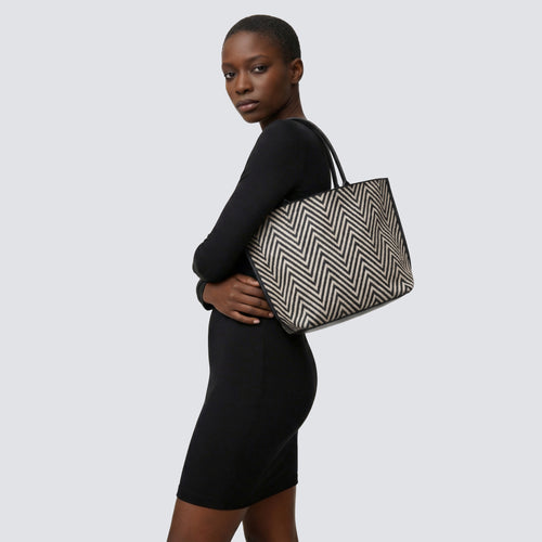 Woman carrying a black and brown chevron knit tote bag with a casual outfit