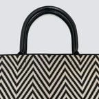 Close-up of the black and brown chevron knit pattern and black handles on a tote bag