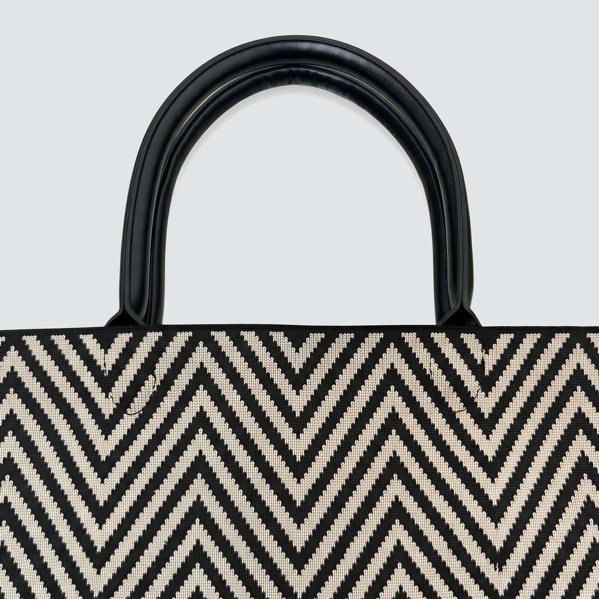 Close-up of the black and brown chevron knit pattern and black handles on a tote bag