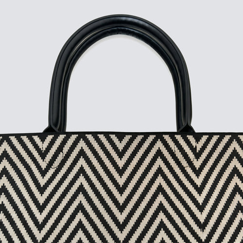 Close-up of the black and brown chevron knit pattern and black handles on a tote bag