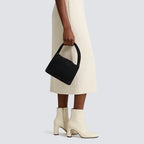 Woman styling a minimalist black knit mini bag with a simple evening outfit