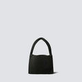 Minimalist black knit mini bag with a curved top handle on a simple product background