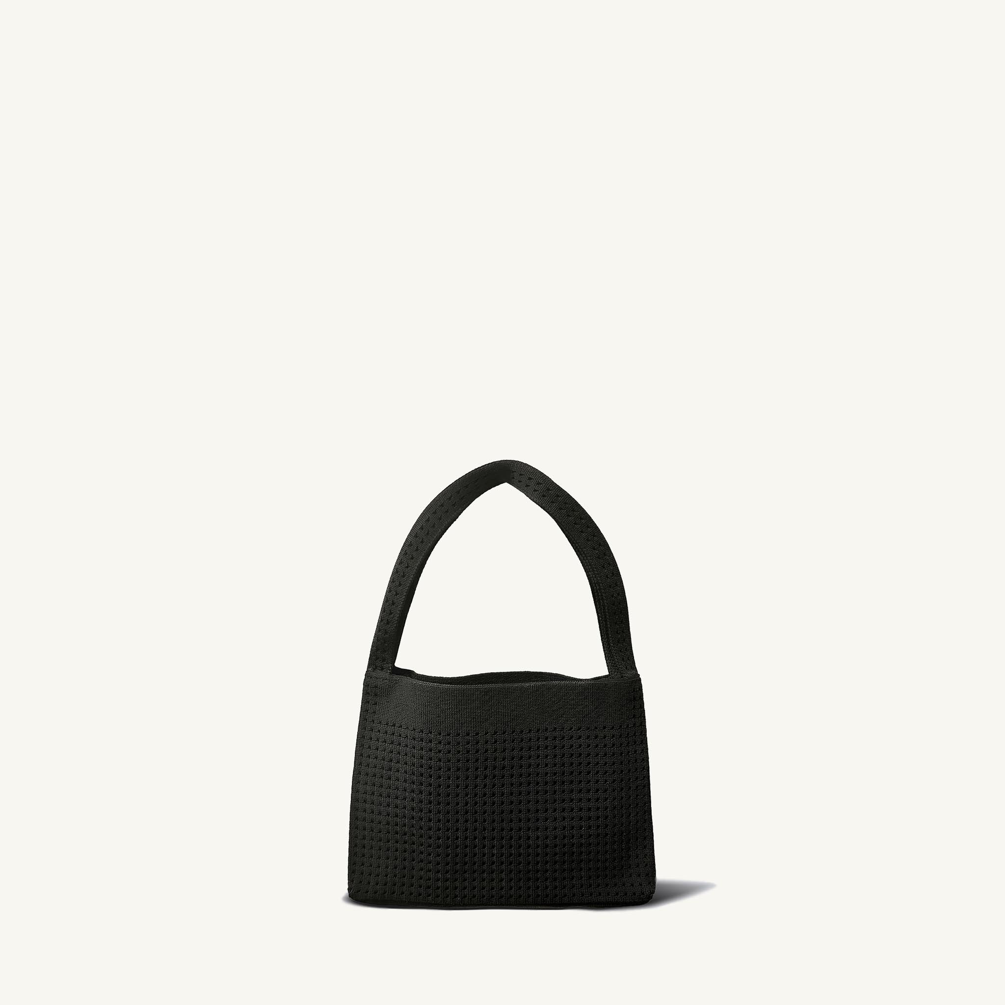 Minimalist black knit mini bag with curved top handle, front view