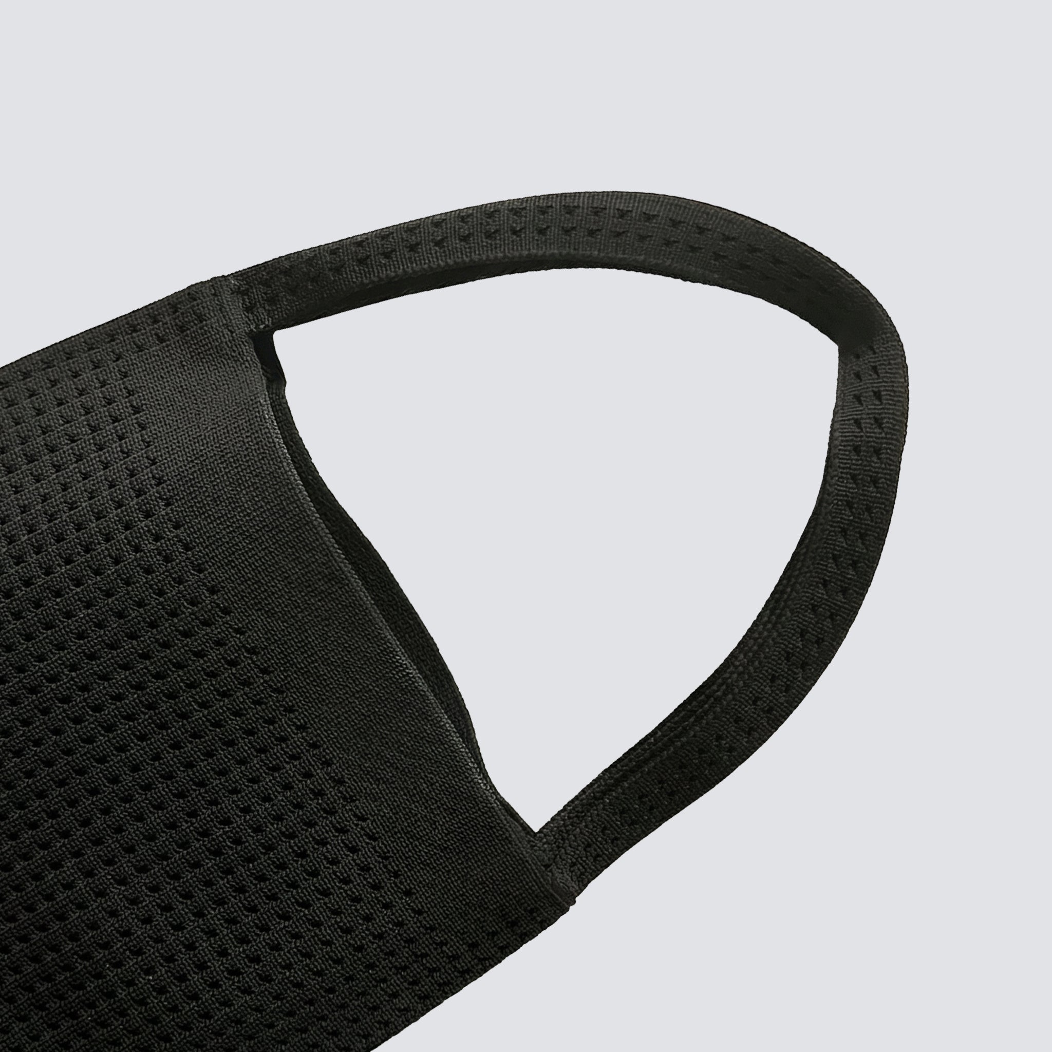 Curved top handle detail on a minimalist black knit mini bag