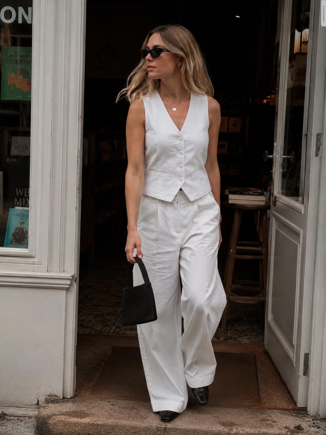 Woman carrying a minimalist black knit mini bag by hand while exiting a bookstore