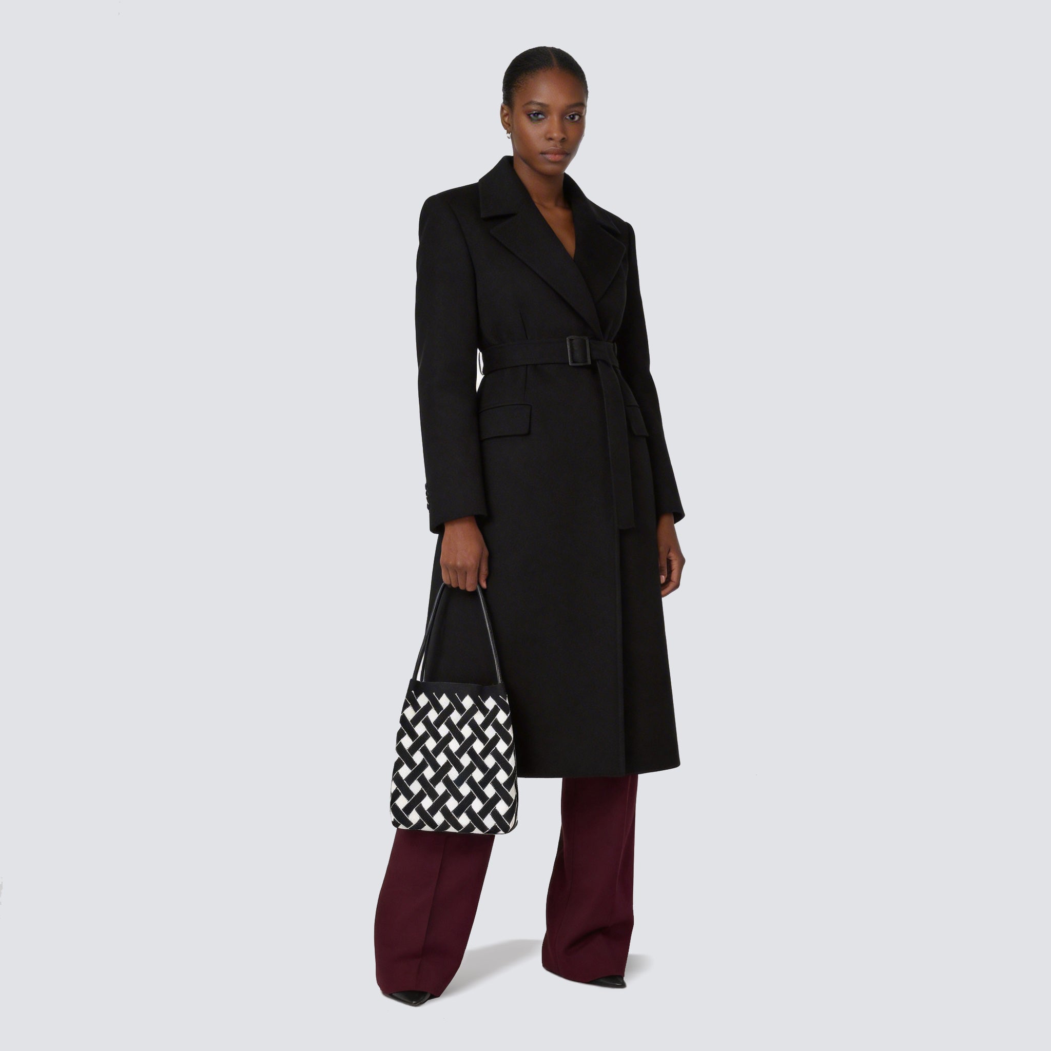 Woman carrying a black and white checkerboard knit tote bag with an everyday outfit