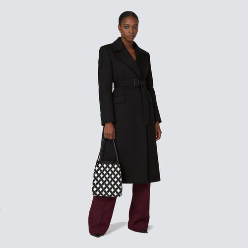 Woman carrying a black and white checkerboard knit tote bag with an everyday outfit