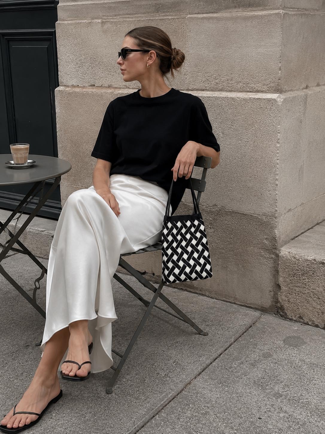 Woman carrying a black and white checkerboard knit tote bag at a cafe