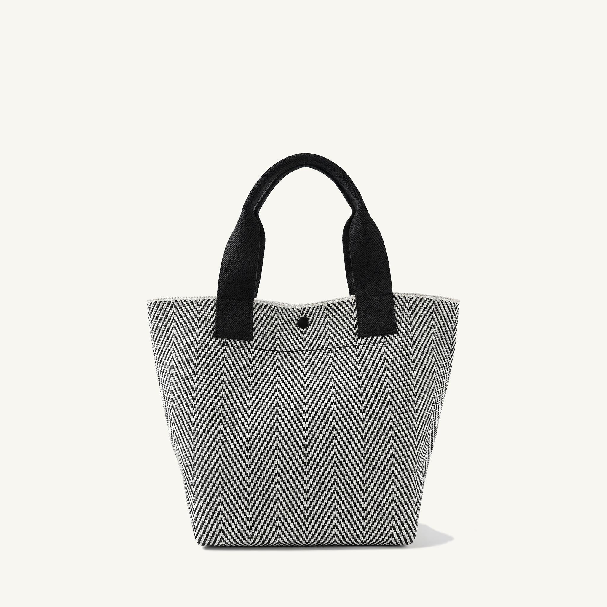 Textured black and white herringbone knit tote bag with black handles, front view