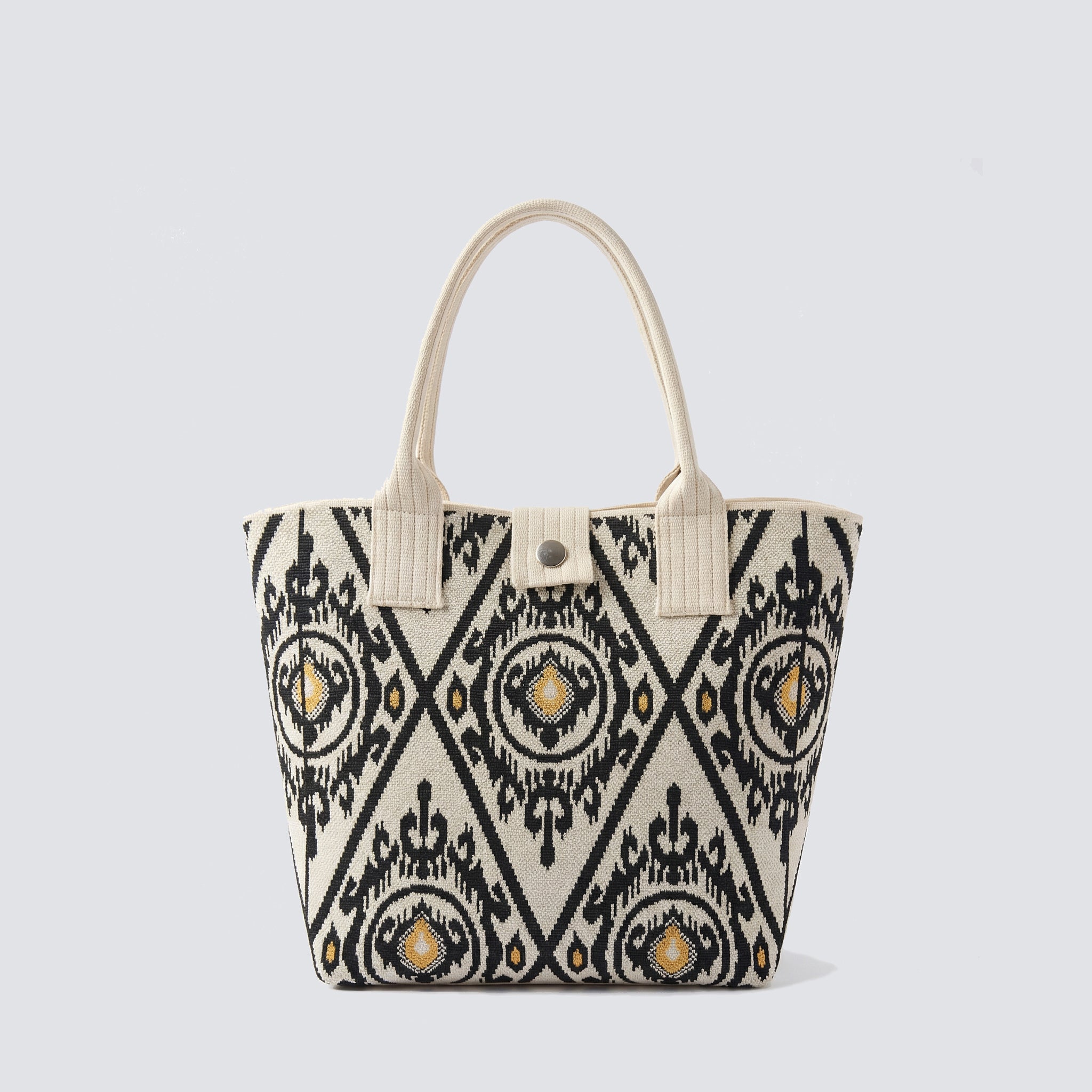 Black and white patterned knit tote bag with long handles on a simple product background
