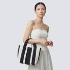 Woman styling a black and white striped knit tote bag with a casual everyday outfit
