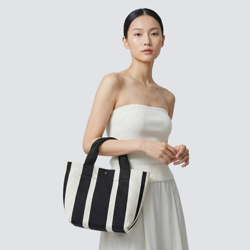 Woman styling a black and white striped knit tote bag with a casual everyday outfit