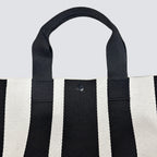 Side view of a black and white striped knit tote bag with short handles
