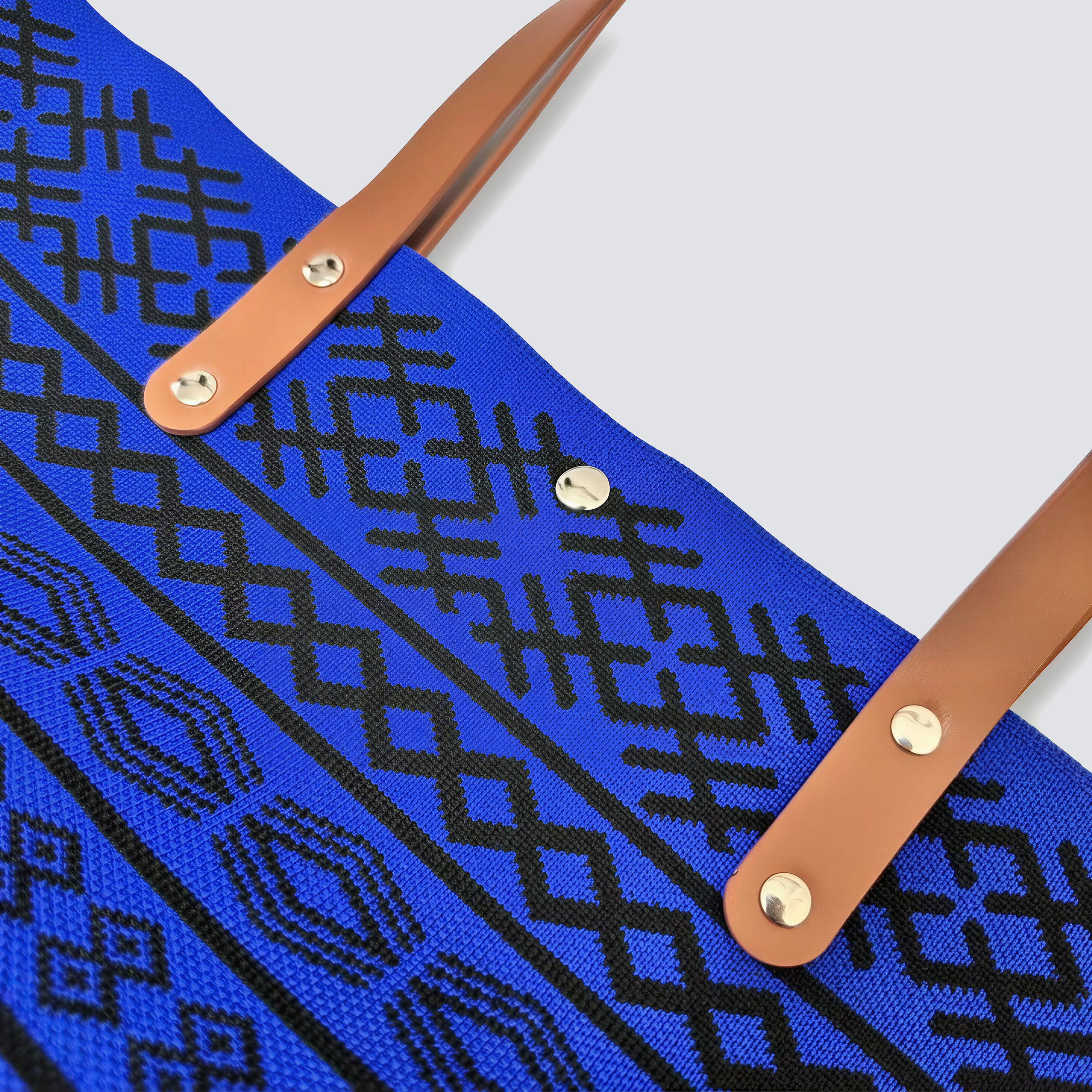 Close-up of the blue bohemian knit pattern and brown handles on a tote bag