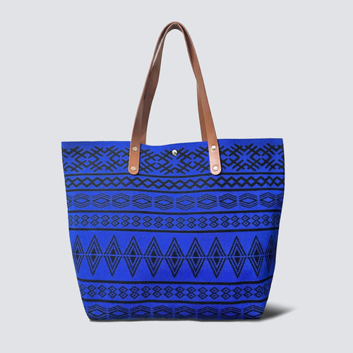 Blue bohemian patterned knit tote bag with brown handles on a simple product background
