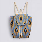 Blue and gold bohemian knit backpack with drawstring and flap closure on a simple product background