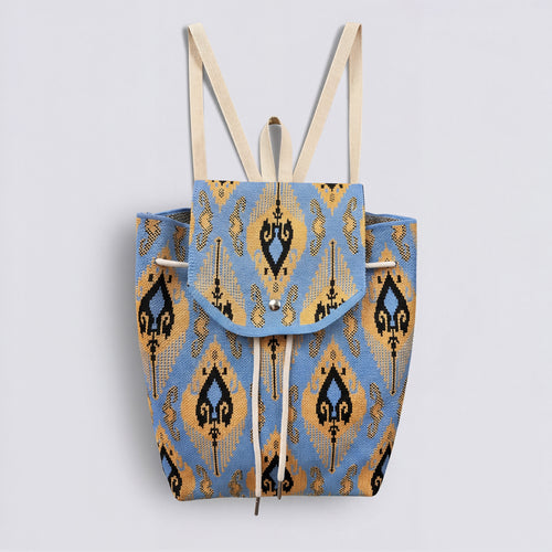 Blue and gold bohemian knit backpack with drawstring and flap closure on a simple product background