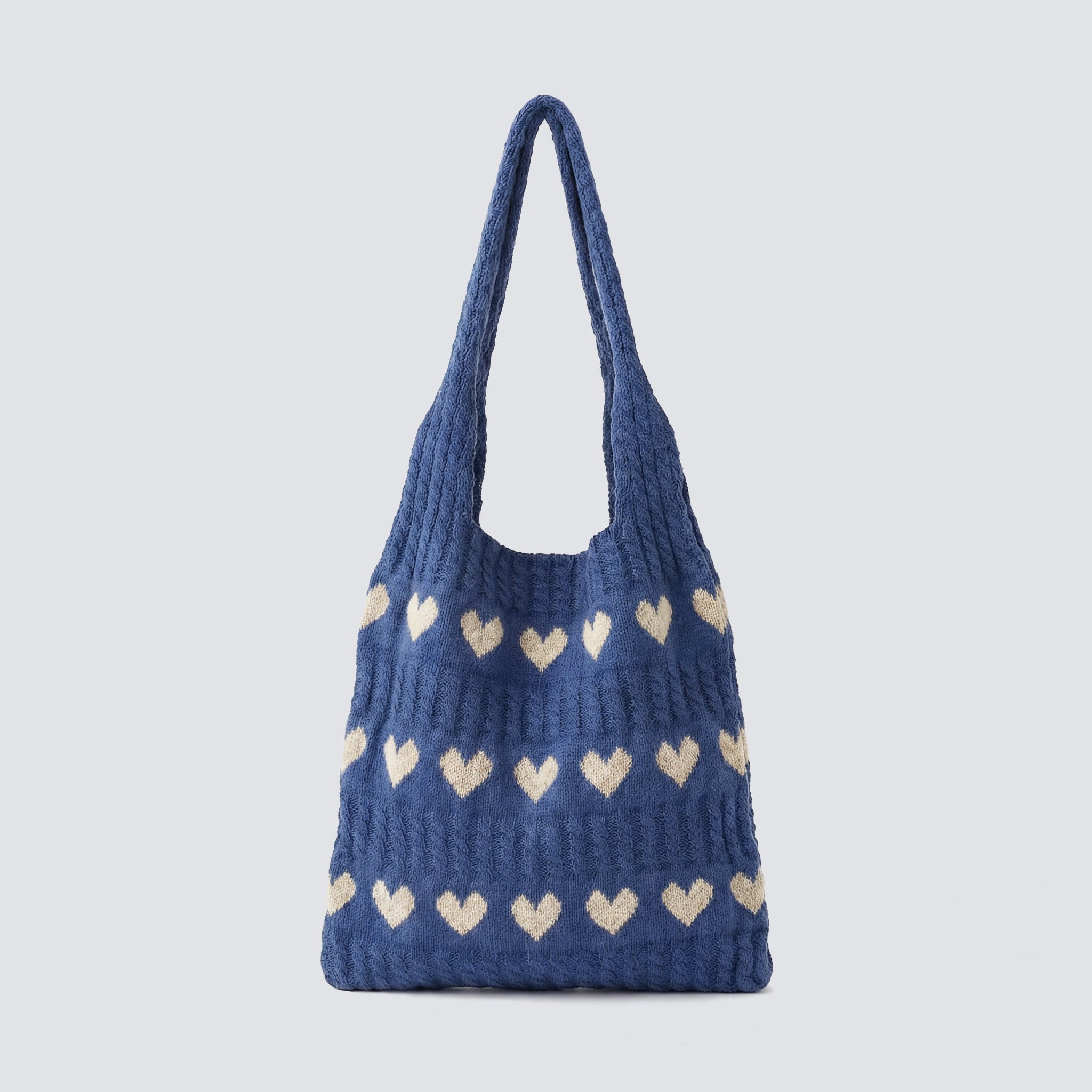 Blue slouchy knit beach bag with ivory heart patterns on a simple product background